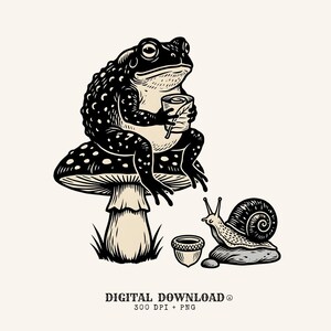 Puede incluir: Una ilustración en negro y crema de un sapo sentado sobre una seta, sosteniendo una taza, con un caracol sobre una roca y una bellota cerca. El texto inferior dice DIGITAL DOWNLOAD 300 DPI + PNG. El diseño presenta líneas de alto contraste.