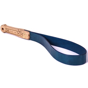 May include: A blue leather camera strap with a wooden handle. The handle has the words "KRAVE LAPC" engraved on it.