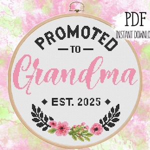 May include: A white cross-stitch embroidery hoop with a black and pink design. The text reads "Promoted to Grandma - Est. 2025".