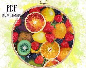Puede incluir: Un aro de bordado redondo lleno de una variedad colorida de frutas, incluyendo naranjas, limones, kiwi y fresas. La fruta está dispuesta en un patrón circular y está rodeada por un aro de madera.