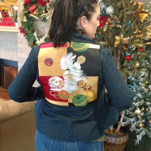 May include: A denim jacket with a colorful embroidered patch on the back. The patch features a white dog with gold and black accents. The dog is surrounded by red, green, and gold circles.
