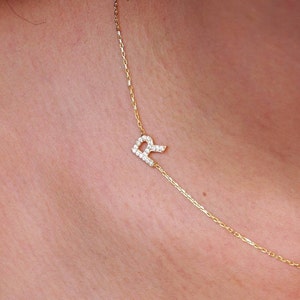 May include: A gold chain necklace with a letter 'R' pendant encrusted with small clear stones.
