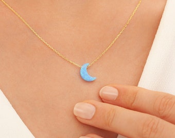 Puede incluir: Un delicado collar de cadena de oro con un colgante de media luna hecho de ópalo azul.