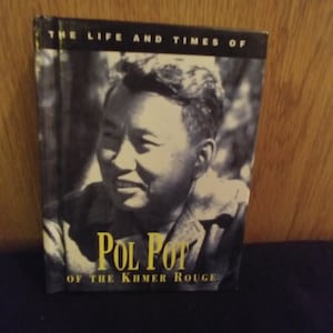 May include: A black and white photograph of Pol Pot, the leader of the Khmer Rouge, on the cover of a book titled "The Life and Times of Pol Pot of the Khmer Rouge".