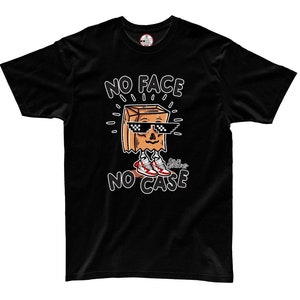 May include: Black t-shirt with a cartoon illustration of a brown paper bag wearing sunglasses and sneakers. The text "NO FACE NO CASE" is printed on the shirt.