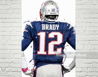 May include: A watercolor-style illustration of Tom Brady, a football player, wearing a blue and white New England Patriots jersey with the number 12 on the back. The jersey has a pink ribbon on the helmet. The background is white with blue and white paint splatters.