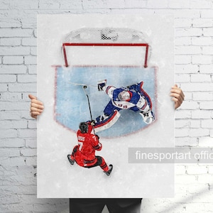 May include: A hockey-themed art print featuring two players in action. One player is in a red uniform, and the other is in a blue and white uniform. The artwork depicts a goal attempt with a net in the background. The print is held by a person.