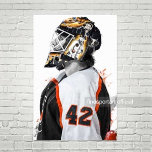 Puede incluir: Una ilustración en blanco y negro de un portero de hockey con una máscara con el número 42 en su camiseta. La máscara está decorada con una variedad de diseños, incluyendo una cabeza de toro, un palo de hockey y el número 1. El portero está mirando hacia la izquierda de la imagen. El fondo es blanco con salpicaduras de pintura naranja y roja.