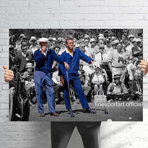 May include: A black and white photograph with selective blue colouring featuring two golfers in blue cardigans and trousers standing on a course with a crowd in the background. The text "finesportart official" is printed in the bottom right corner.