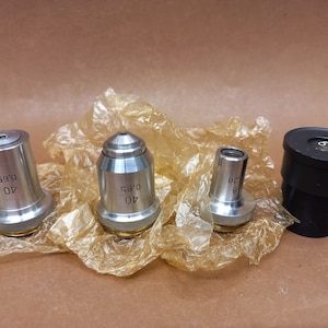 May include: Four microscope objectives, two silver 40x 0.65 objectives, one silver 8x 0.20 objective, and one black Kist objective.
