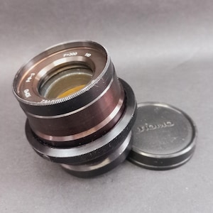 May include: A white ceramic mug with a black handle and the text "But First, Coffee" in a black, bold font. The mug is on a white surface.