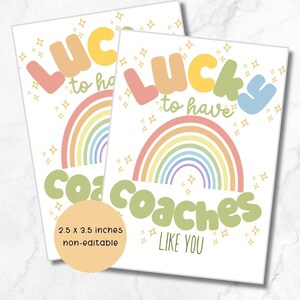 Puede incluir: Dos tarjetas blancas con el texto "Lucky to have coaches like you" en letras de colores. Cada tarjeta presenta un arcoíris. Las tarjetas miden 6,35 x 8,89 cm.
