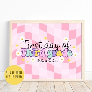May include: A rectangular sign in a light wood frame featuring a pink and white wavy checkerboard background. The text reads First day of Third grade 2026-2027 in black and multicolored bubble letters, accented with white daisies and yellow stars. 8 x 10 inches.
