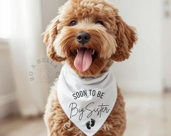 May include: A light brown dog wearing a white bandana with the text "SOON TO BE Big Sister" in black script. The bandana also features two black footprints. The dog has a pink tongue sticking out.