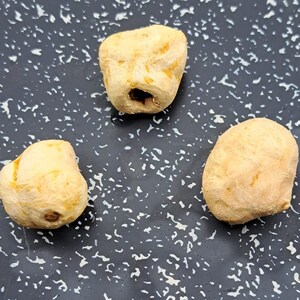 Könnte beinhalten: Drei hellbraune, unregelmäßig geformte, getrocknete Früchte oder Gemüse auf einer dunkelgrauen, gesprenkelten Oberfläche.