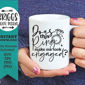 May include: White ceramic mug with black text that reads "Does this ring make me look engaged?" with a diamond ring illustration.