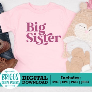 May include: Pink t-shirt with the text "Big Sister" in a retro font. The shirt is on a white wooden surface with a brown knitted hat and brown mittens.