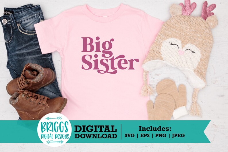 May include: Pink t-shirt with the text "Big Sister" in a retro font. The shirt is on a white wooden surface with a brown knitted hat and brown mittens.