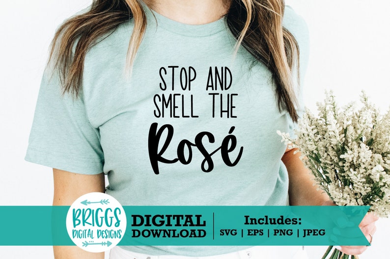 May include: A light blue t-shirt with the text "Stop and Smell the Ros&eacute;" in black. The shirt is being worn by a person holding a bouquet of white flowers.