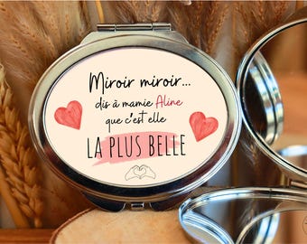 May include: A silver compact mirror with a white background and pink hearts. The text on the mirror reads "Miroir miroir... dis à mamie Aline que c'est elle LA PLUS BELLE".
