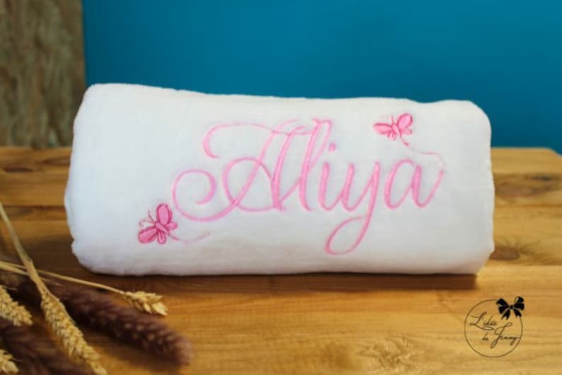 May include: White plush blanket with pink embroidery of the name "Aliya" and pink butterfly designs.