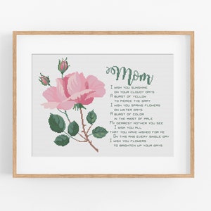 Puede incluir: Una obra de arte en punto de cruz enmarcada con una rosa rosa y la palabra "Mamá" en escritura verde. La obra de arte incluye un poema con sentimientos de amor y deseos de felicidad, perfecto para el Día de la Madre.