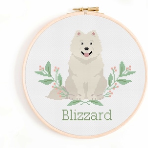 May include: Cross stitch pattern of a white dog with pink accents, sitting with green leafy branches and pink berries on either side. The dog's name, "Blizzard", is stitched below the dog.
