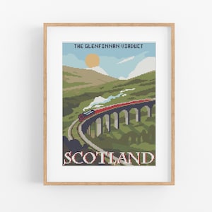 May include: A framed print featuring a pixelated illustration of the Glenfinnan Viaduct in Scotland. A red train crosses the bridge, with the word "SCOTLAND" at the bottom. The sky is blue with a yellow sun.
