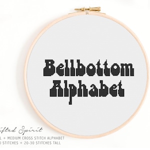 May include: A black and white cross stitch pattern for the phrase "Bellbottom Alphabet". The pattern is framed in a wooden embroidery hoop. The text "Lifted Spirit" is below the hoop, along with the text "SMALL + MEDIUM CROSS STITCH ALPHABET 10-20 STITCHES + 20-30 STITCHES TALL".