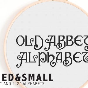 以下が含まれることがあります： 白い刺繍枠に、黒いクロスステッチで「Old Abbey Alphabet」という文字が刺繍されています。その下に「Med & Small < 1" and 1-2" Alphabets」という文字が刺繍されています。