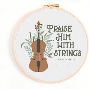 May include: A cross-stitch embroidery hoop with a brown violin and green foliage. The text reads "Praise Him With Strings Psalm 150:4".