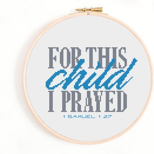 Puede incluir: Un aro de bordado blanco con un diseño de punto de cruz que dice "For this child I prayed 1 Samuel 1:27". Las palabras "child" y "prayed" están en hilo azul, mientras que el resto del texto está en hilo gris.