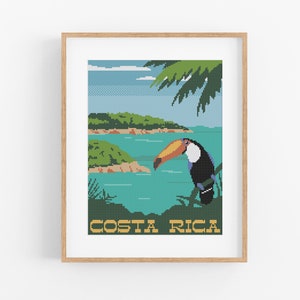 May include: A framed cross-stitch design featuring a toucan perched on a branch with a tropical island scene in the background. The text "COSTA RICA" is written in yellow at the bottom of the design.