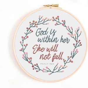 Könnte beinhalten: Ein weißer Stickrahmen mit einem floralen Kranzdesign in Rosa- und Blautönen. Der Text "Gott ist in ihr, sie wird nicht fallen, Psalm 46:5" ist in der Mitte gestickt.