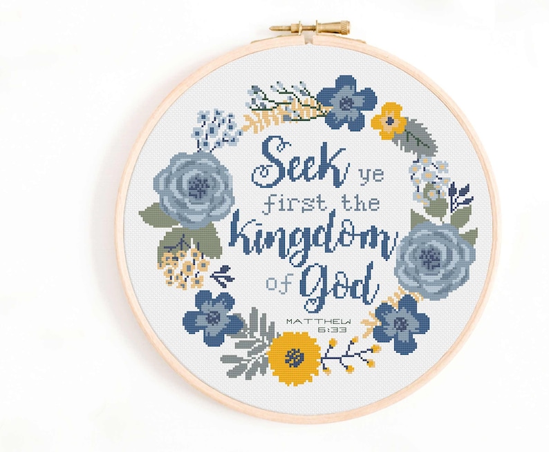 May include: Cross stitch pattern featuring a floral wreath with blue and yellow flowers. The text in the centre reads "Seek ye first the kingdom of God" with the scripture reference "Matthew 6:33".