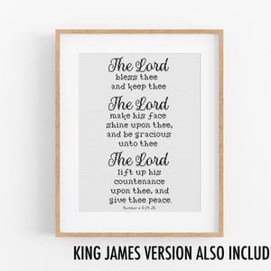 Op de afbeelding: Een printbaar wanddecor ontwerp met een zwart-wit tekstcitaat uit de Bijbel, Numeri 6:24-26. De quote luidt: "De Heer zegene u en behoede u. De Heer laat zijn aangezicht over u schijnen en zij u genadig. De Heer verheffe zijn aangezicht over u en geve u vrede." De tekst is in een decoratief lettertype en is ingelijst in een houten lijst.