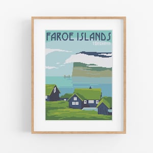 Puede incluir: Un póster enmarcado con una imagen pixelada de un paisaje con colinas verdes, agua azul y un acantilado. El póster tiene el texto "FAROE ISLANDS" y "TORSHAVN" en azul.