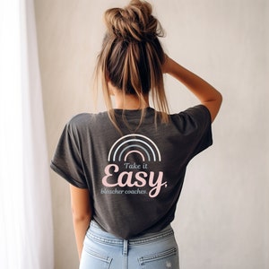 May include: A charcoal grey t-shirt with a rainbow graphic and the text "Take it Easy, bleacher coaches."