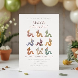 May include: A white rectangular birthday invitation card featuring the text LET'S DIG INTO THE FUN, MASON is turning three!, SATURDAY | MARCH 21ST | 20XX, and nine illustrations of colorful worms wearing party hats and holding birthday items.