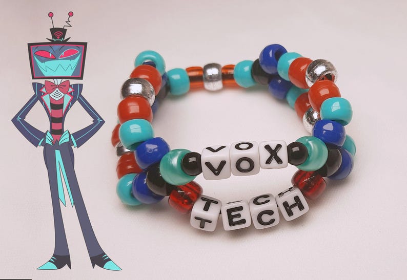 Peut inclure: Un bracelet de perles color&eacute;es avec les mots "VOX TECH" &eacute;pel&eacute;s en perles blanches. Le bracelet pr&eacute;sente des perles rouges, bleues, turquoise, noires et argent&eacute;es. Une illustration d'un personnage de dessin anim&eacute; avec une t&ecirc;te de t&eacute;l&eacute;vision est &agrave; gauche.