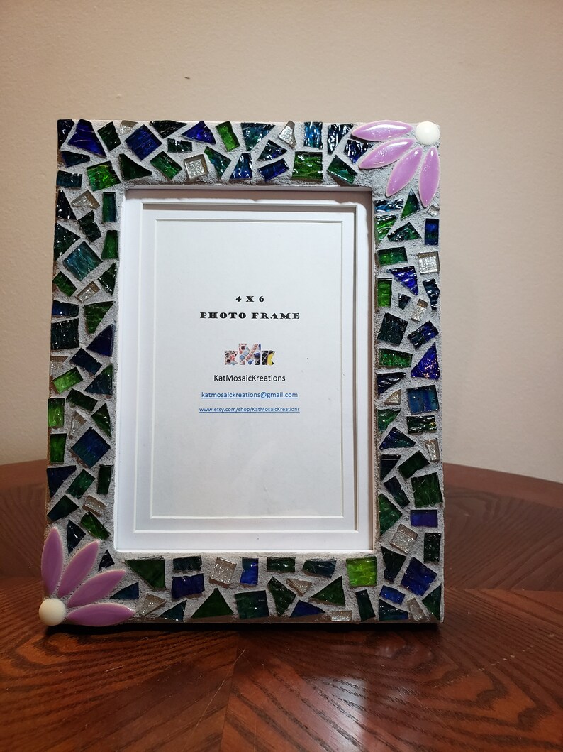 Puede incluir: Un marco de fotos de 4x6 con un dise&ntilde;o de mosaico en tonos de verde, azul y plateado. El marco tiene un dise&ntilde;o de flor rosa en la esquina superior derecha. El marco tiene un paspart&uacute; blanco y un fondo blanco con el texto "4x6 Photo Frame" y el nombre "KatMosaicKreations" con informaci&oacute;n de contacto.
