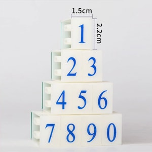 May include: Set of four white plastic number blocks with blue numbers 1 through 9. Each block measures 1.5 inches by 2.2 inches.