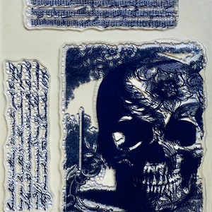 May include: Clear rubber stamp with a black and white image of a skull with flowers and a decorative frame. The text "Fuarcoledri zuattina, 30 coerentes, peart Si rice to vno por la volto di cortes: mandari os potoms solutamente la carrogria de ce for al mandeso, innanmanga de' asen, di quelle rimanete 83" is visible on the stamp.