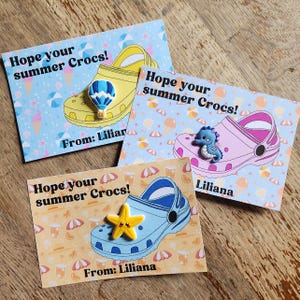 May include: Three cards featuring Crocs shoe illustrations. Each card reads "Hope your summer Crocs!" and "From: Liliana". The Crocs are yellow, pink, and blue, adorned with charms of a hot air balloon, seahorse, and starfish.