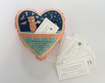 May include: A heart-shaped plush toy with a pocket that holds small cards with inspirational quotes and bible verses. The toy is pink and blue with a bear and stars on the front. The text on the cards reads "I treasure your word in my heart so I won't sin against you".