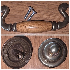 May include: A drawer pull handle featuring a central light brown wood grain barrel with curved metallic ends, accompanied by two silver-colored metal screws. Below, two circular metallic backplates are shown, one displaying the reverse side.