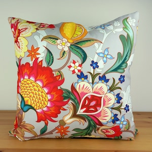 Könnte beinhalten: Ein Dekokissen mit einem Blumenmuster. Das Kissen hat einen grauen Hintergrund mit bunten Blumen, Blättern und Ranken. Die Blumen sind rot, gelb, rosa und blau.