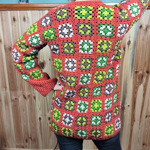 May include: A red, green, and white crocheted cardigan with a granny square pattern.