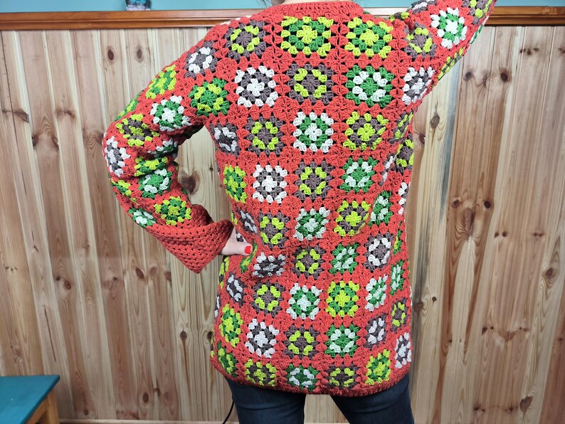 May include: A red, green, and white crocheted cardigan with a granny square pattern.