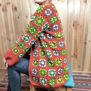 May include: A crocheted cardigan with a granny square pattern in shades of orange, green, white, and brown.
